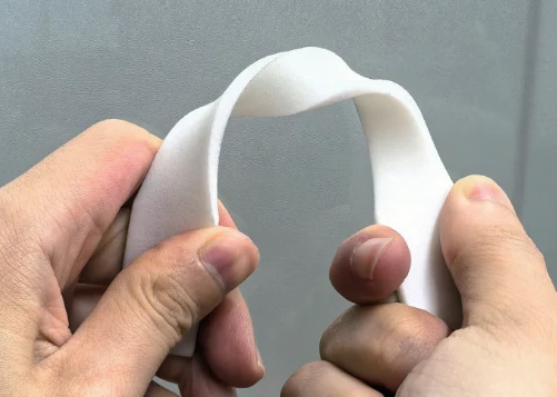 White co-polyamide sample bent by hand to demonstrate flexibility